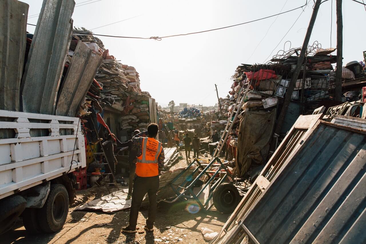 Workmen standing near pile of metal scrap